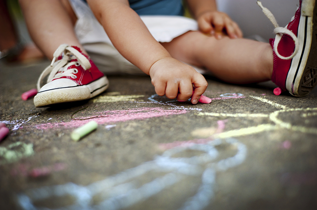 a child drawing on the floor with chalk