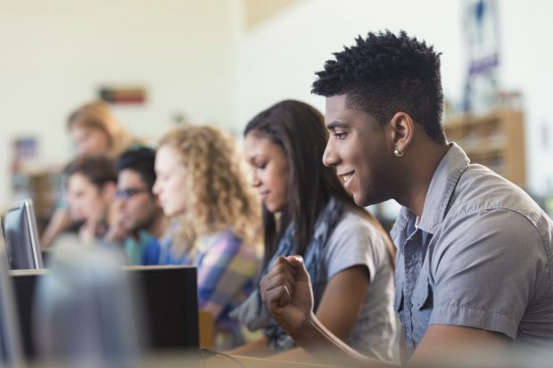 teenagers working on computers, looking pleased with what they are doing