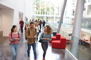 three university students walking in a lobby area